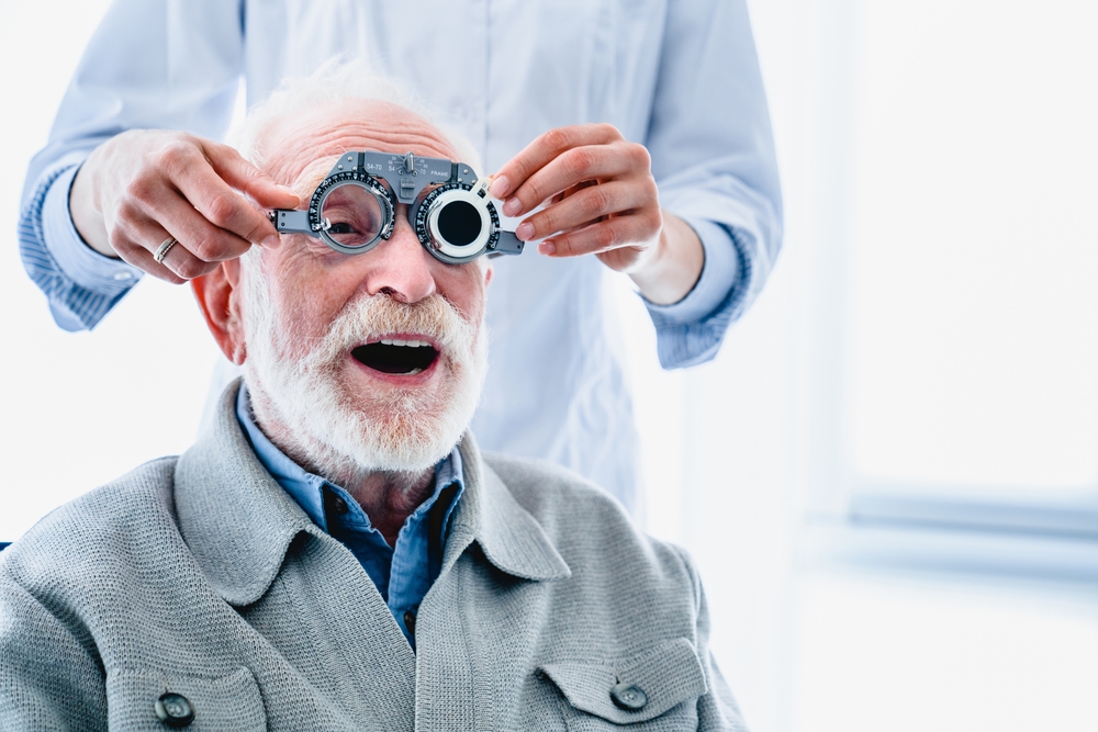 An elderly male patient undergoes a detailed vision assessment using a phoropter during a routine visit with an eye care professional, ensuring accurate prescription updates and overall eye health evaluation - Comprehensive Eye Exams